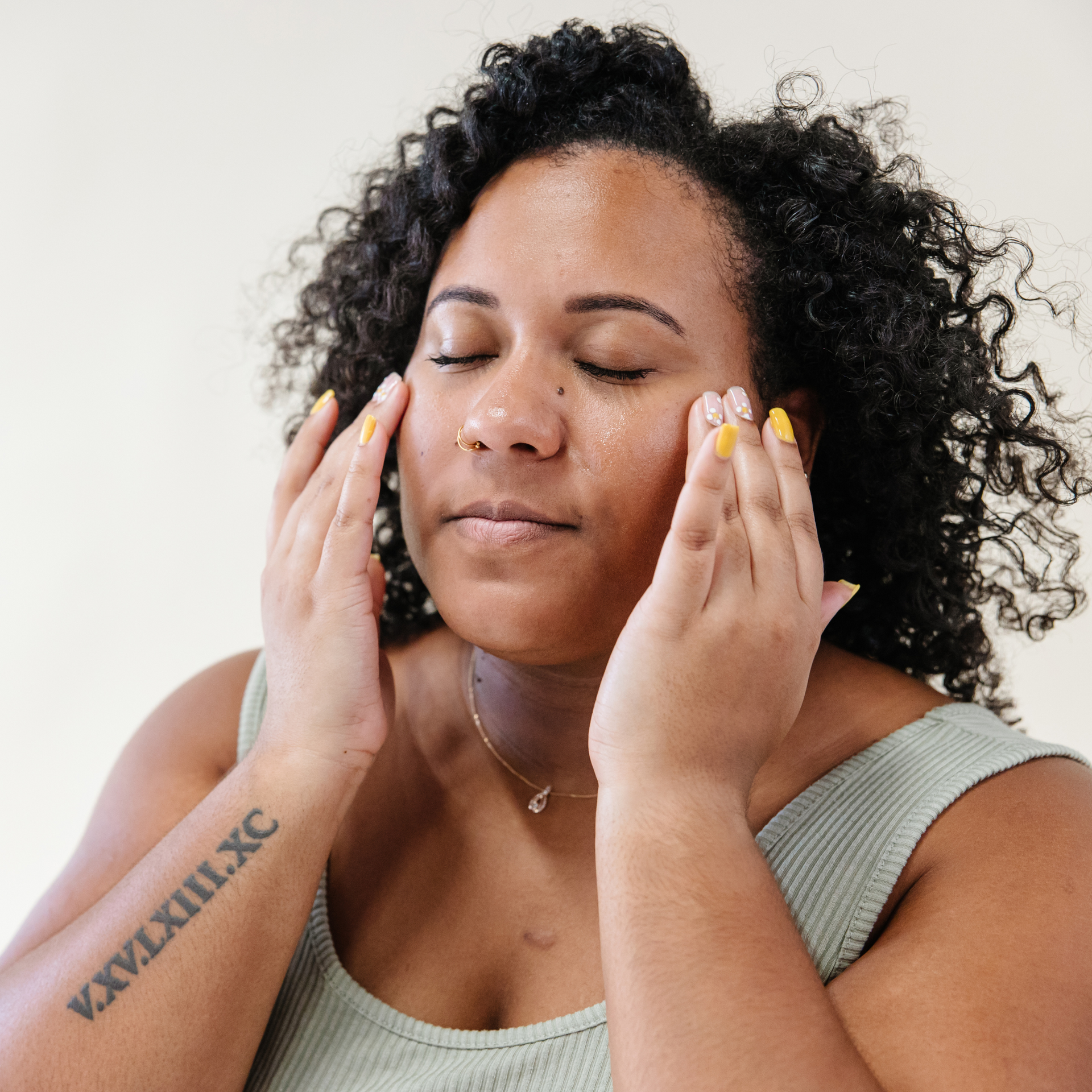 A woman with a tattoo on her arm has her eyes closed