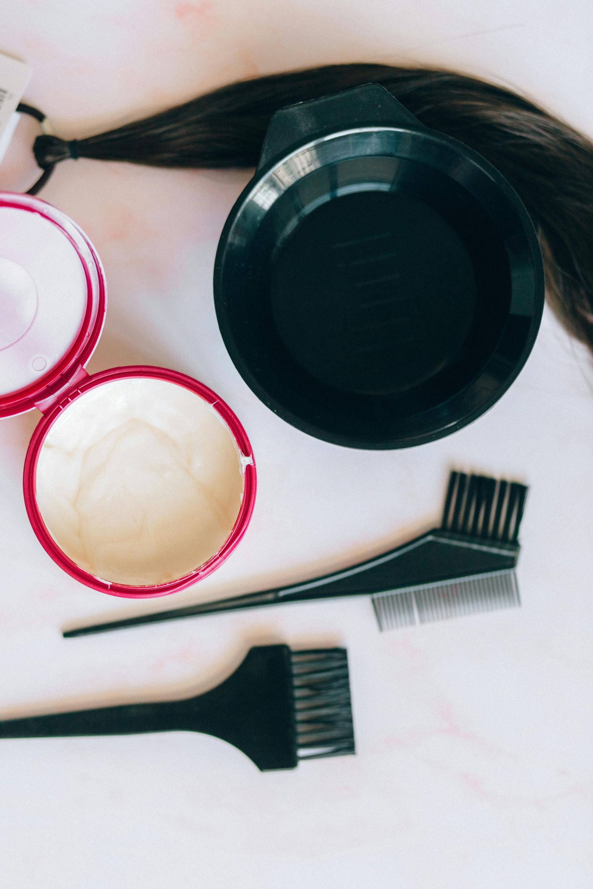 A bowl of hair dye next to a brush and comb