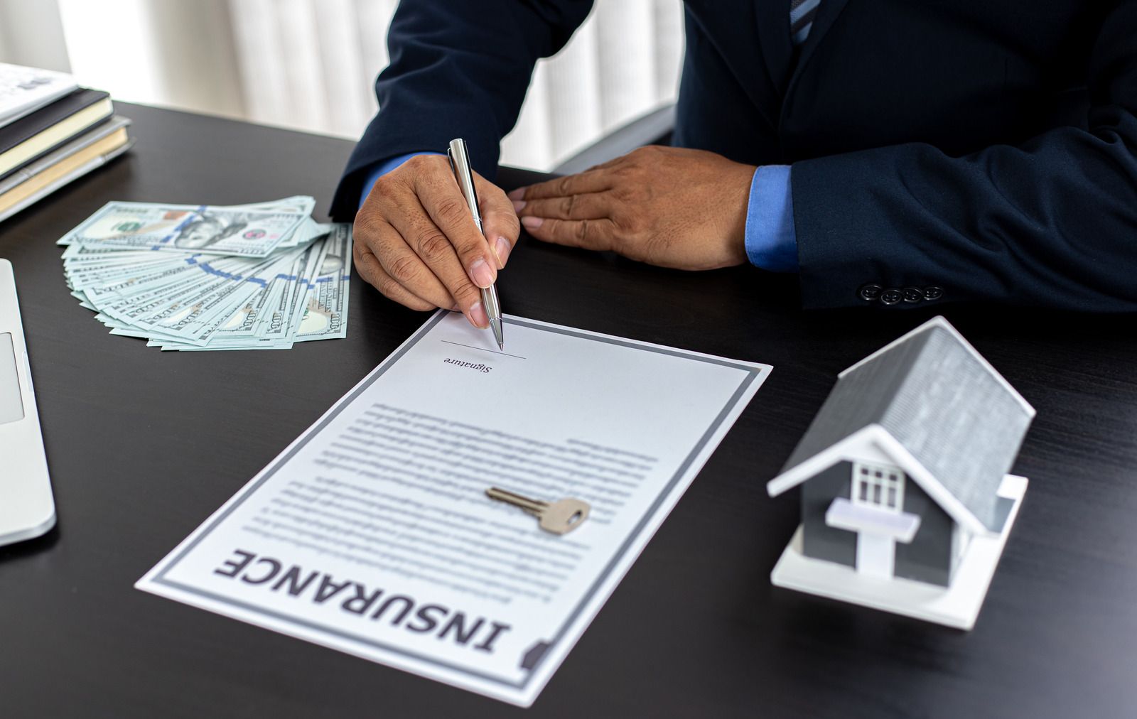 Property insurance policy with pen on wooden desk, blue cup and calculator in the background.
