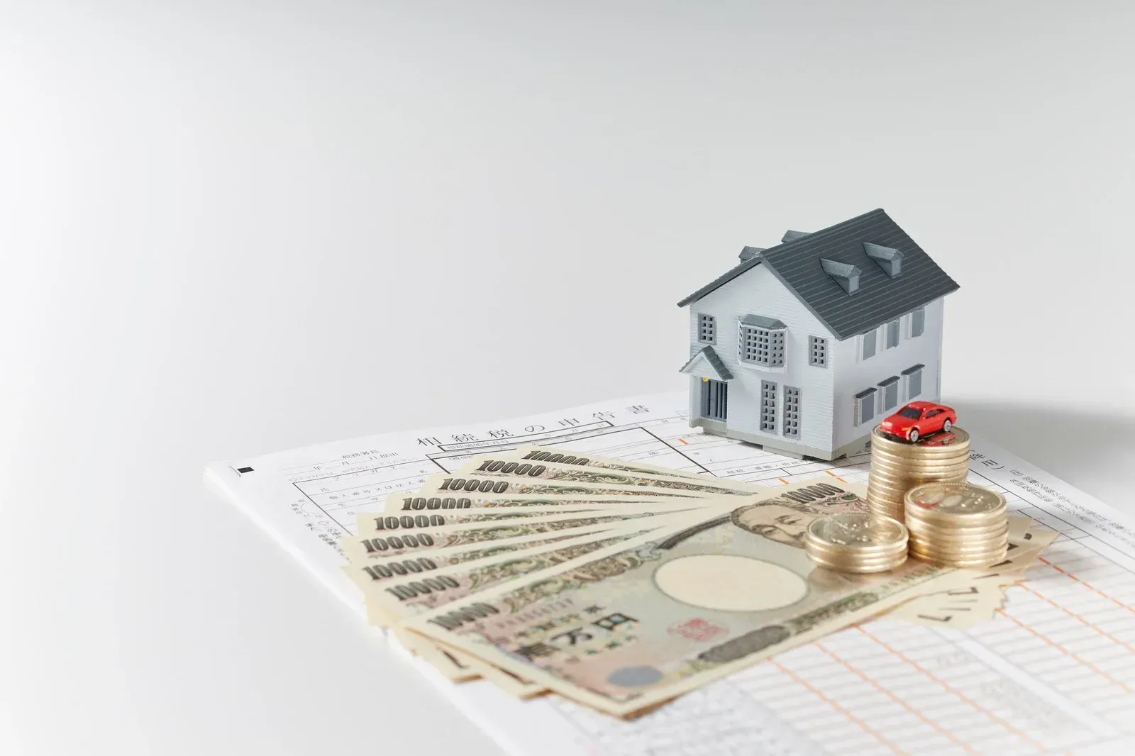 Miniature house with money, coins, and a toy car on a ledger.