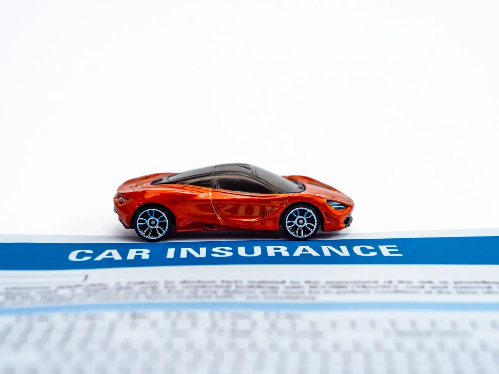 Toy orange sports car on a car insurance document with 