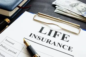 Life insurance form with pen, notepad, money, and pen.