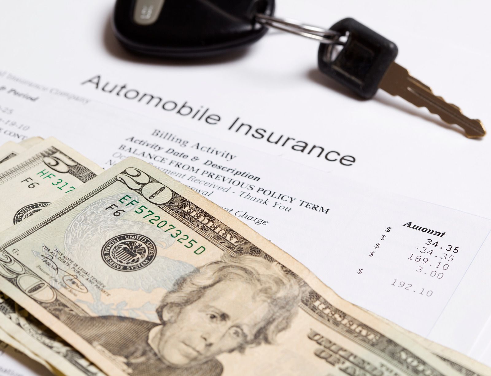 Automobile insurance bill and cash ($20 bills) with car keys.
