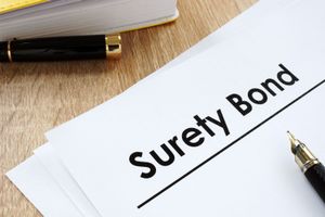 "A document labeled 'Surety Bond' with a pen and other paperwork on a wooden desk."