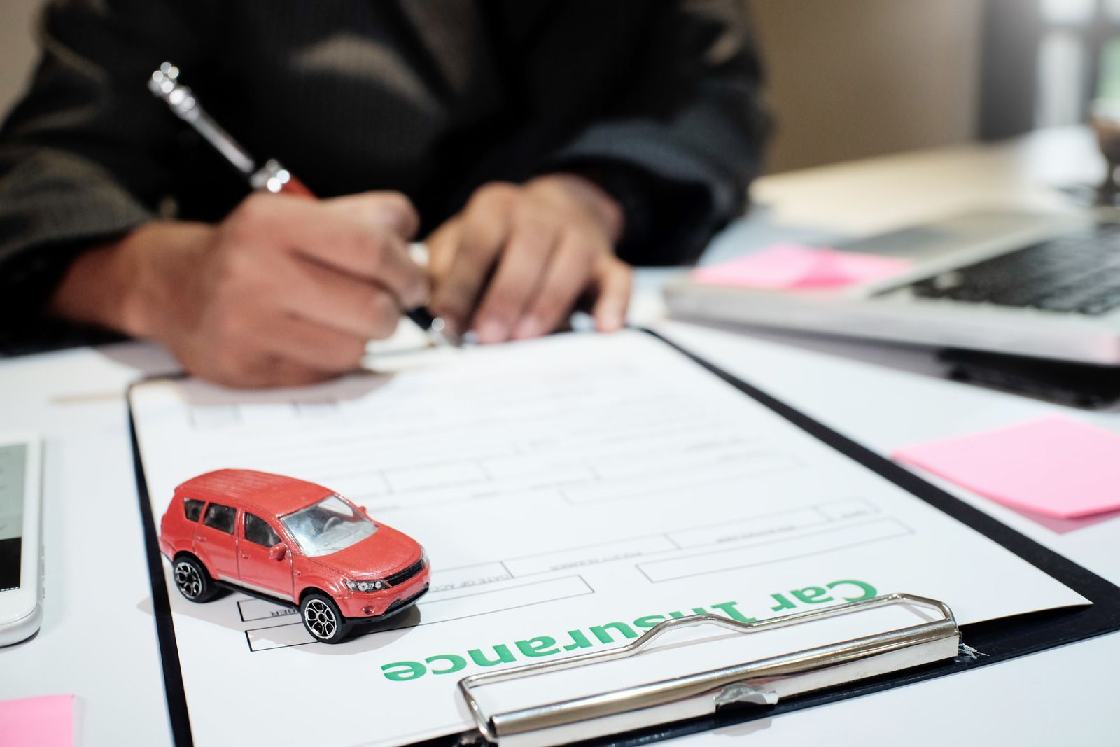 A pen on an auto insurance quote request form, blue and white, ready to be filled out.