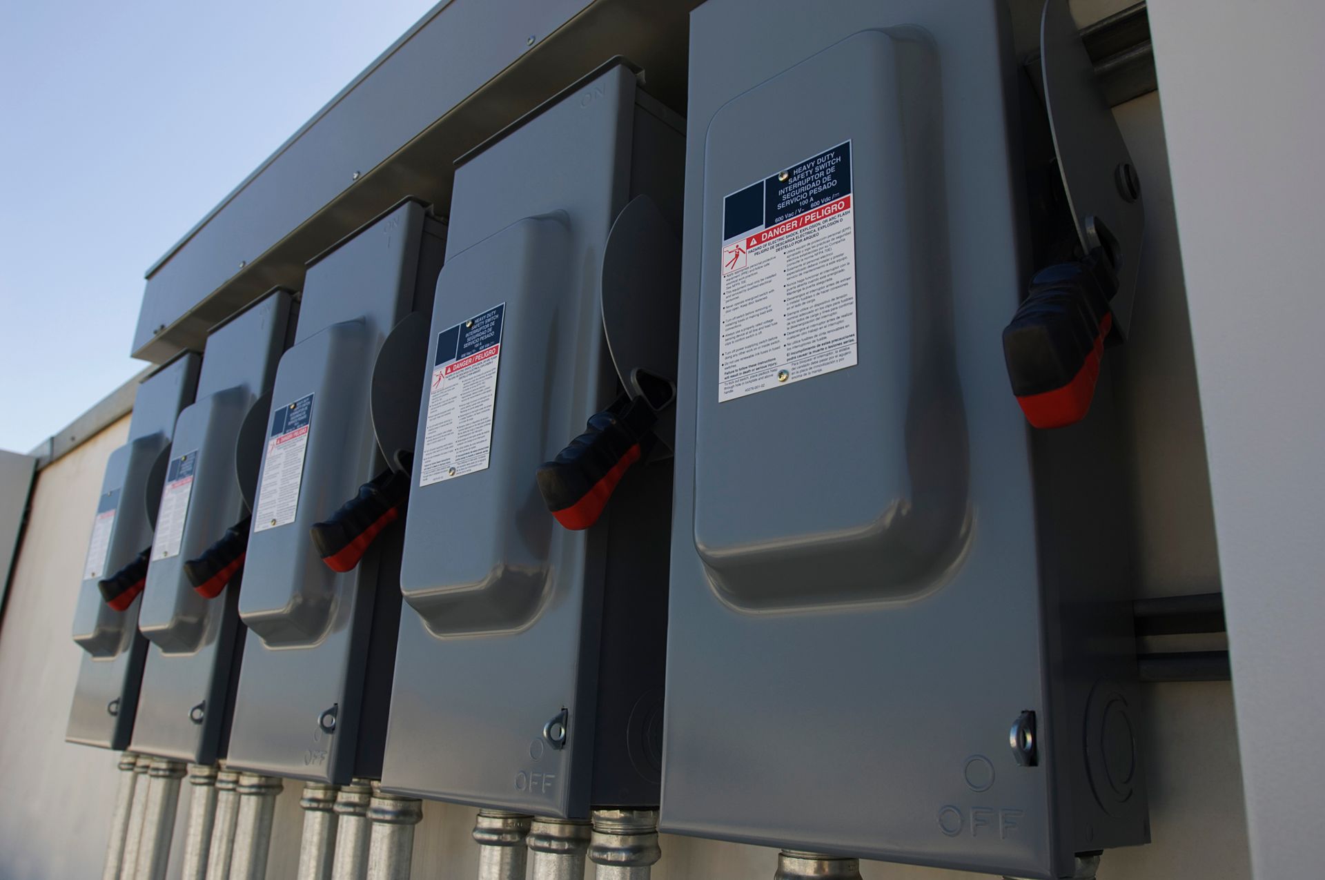 a row of electrical boxes with warning labels on them