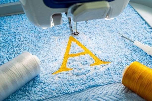 Alphabet logo on towel, showcasing custom embroidery services with precise machine stitching.
