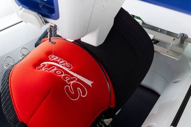 Embroidered cap on machine, highlighting custom embroidery services with precise stitching detail.