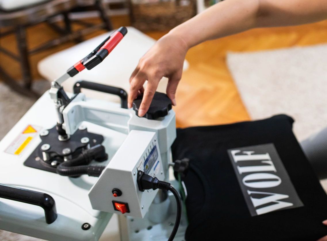 A woman is using a machine to print a shirt in a factory.