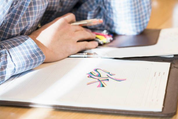 A man is sitting at a table drawing on a piece of paper.