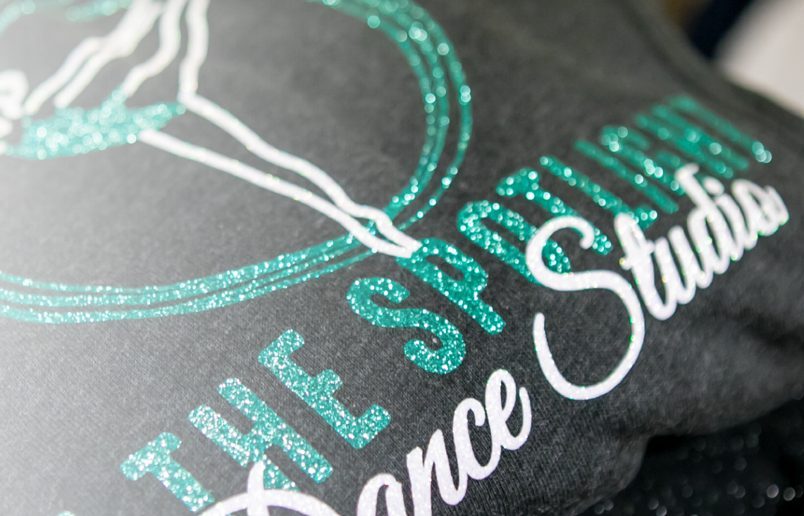 A close up of a pillow with a dance studio logo on it