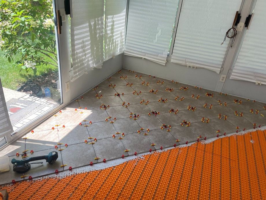 Bright room with white blinds, orange tile floor, and a power drill near a sunlit window.