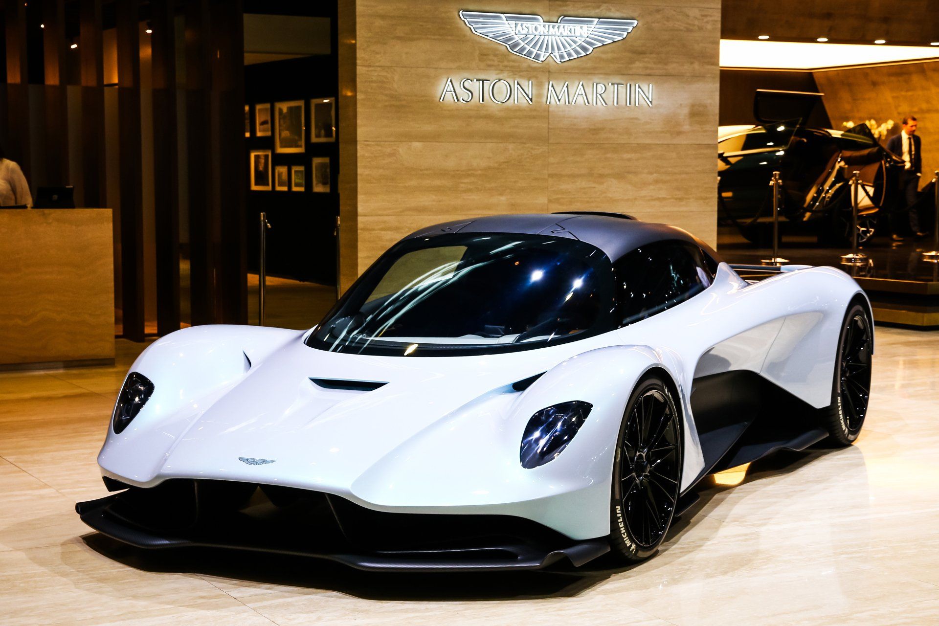 A white sports car is parked in front of a sign that says aston martin