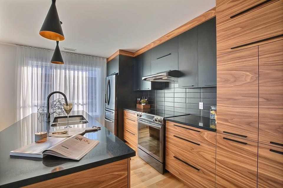 Une cuisine avec armoires en bois, comptoirs noirs, appareils électroménagers en acier inoxydable et un livre sur le comptoir.