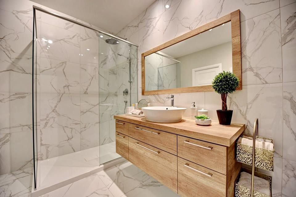 Une salle de bain avec lavabo, miroir et douche à l'italienne.