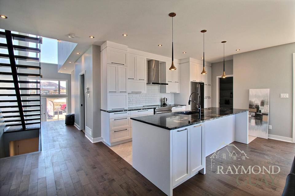 Une cuisine avec armoires blanches et comptoirs en granit noir.