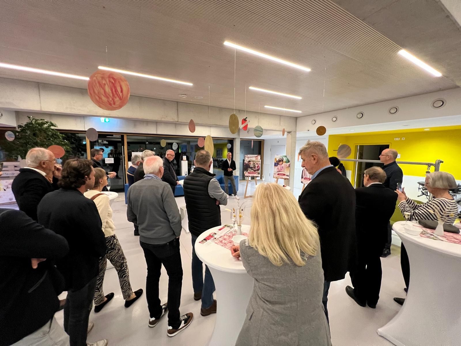 Menschen versammeln sich in einem Gebäude, möglicherweise bei einer Veranstaltung oder einem Empfang. 