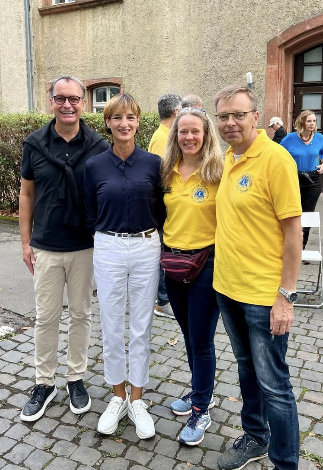 Eine Gruppe von Menschen steht nebeneinander auf einer Kopfsteinpflasterstraße.