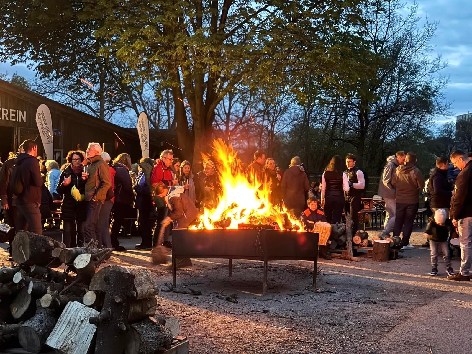 Eine große Gruppe von Menschen versammelt sich um ein großes Feuer