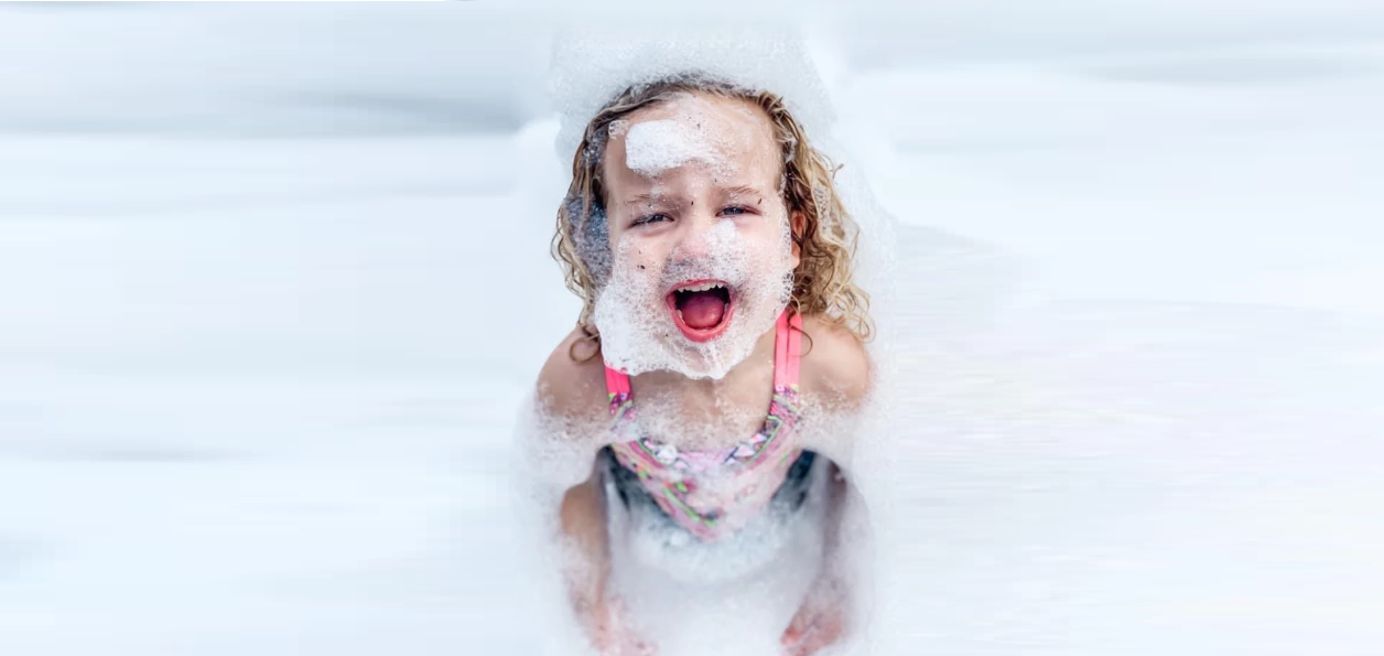 A little girl is playing in a pool of foam.