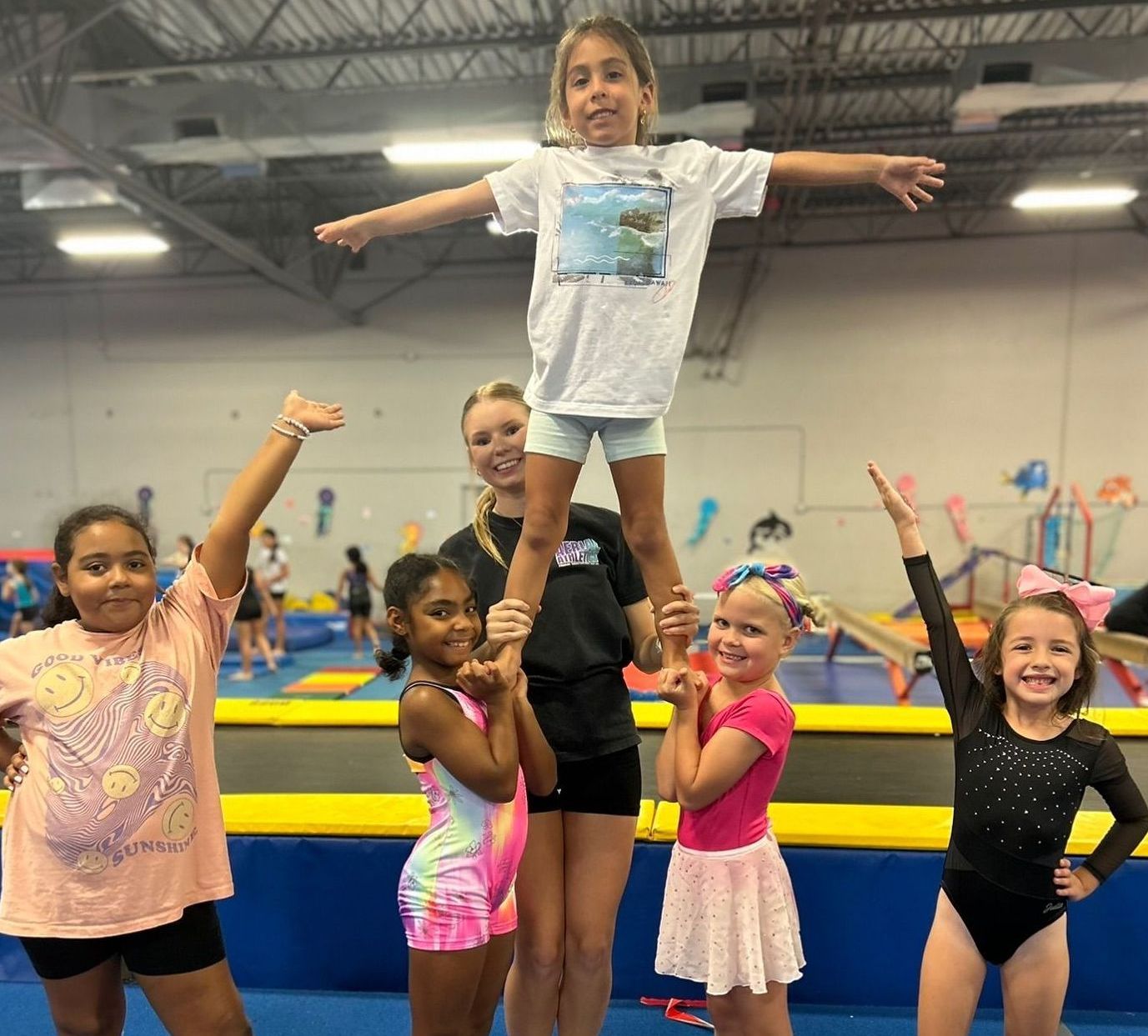 A woman is helping a young girl do a handstand in a gym