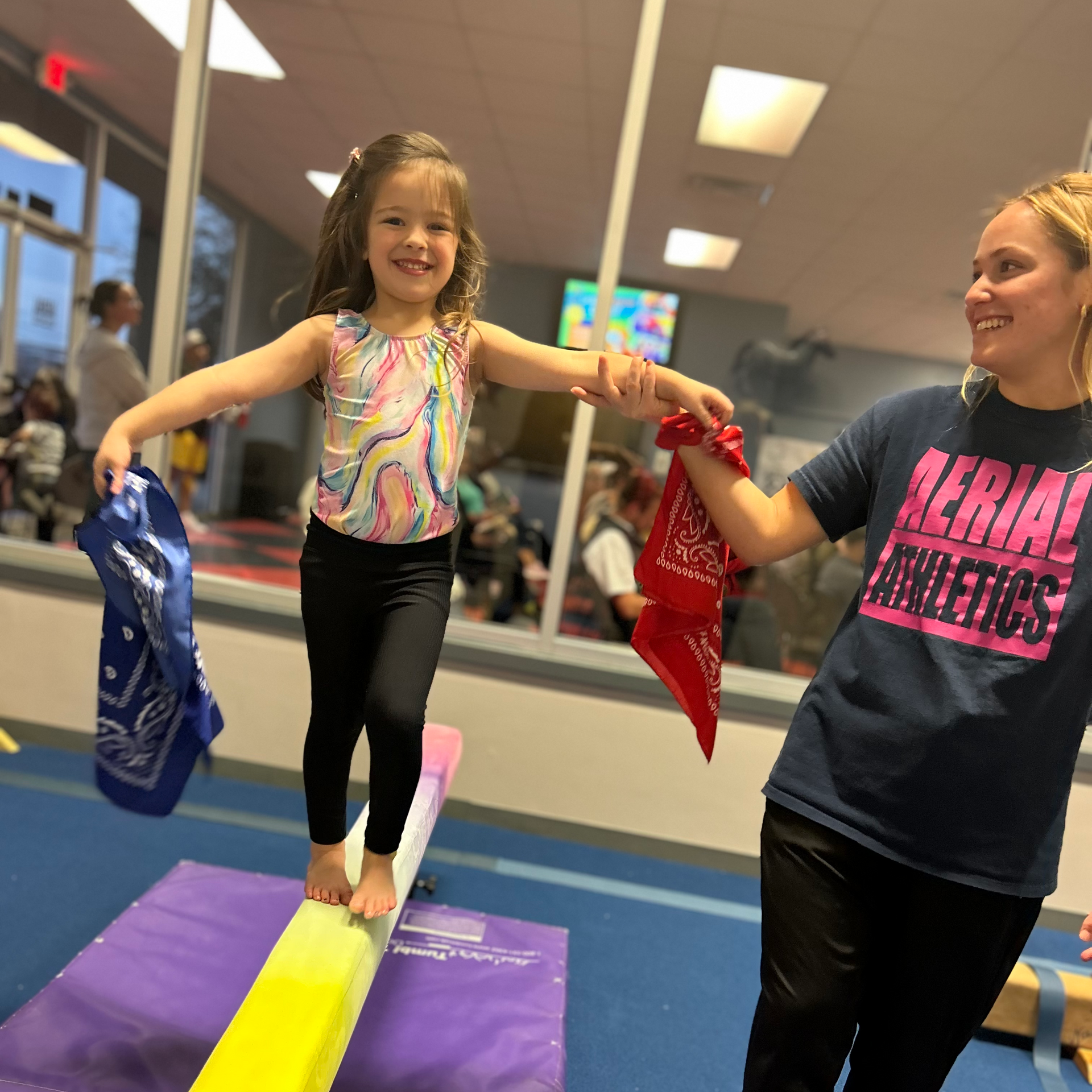 Two little girls wearing masks and capes are playing on a balance beam.