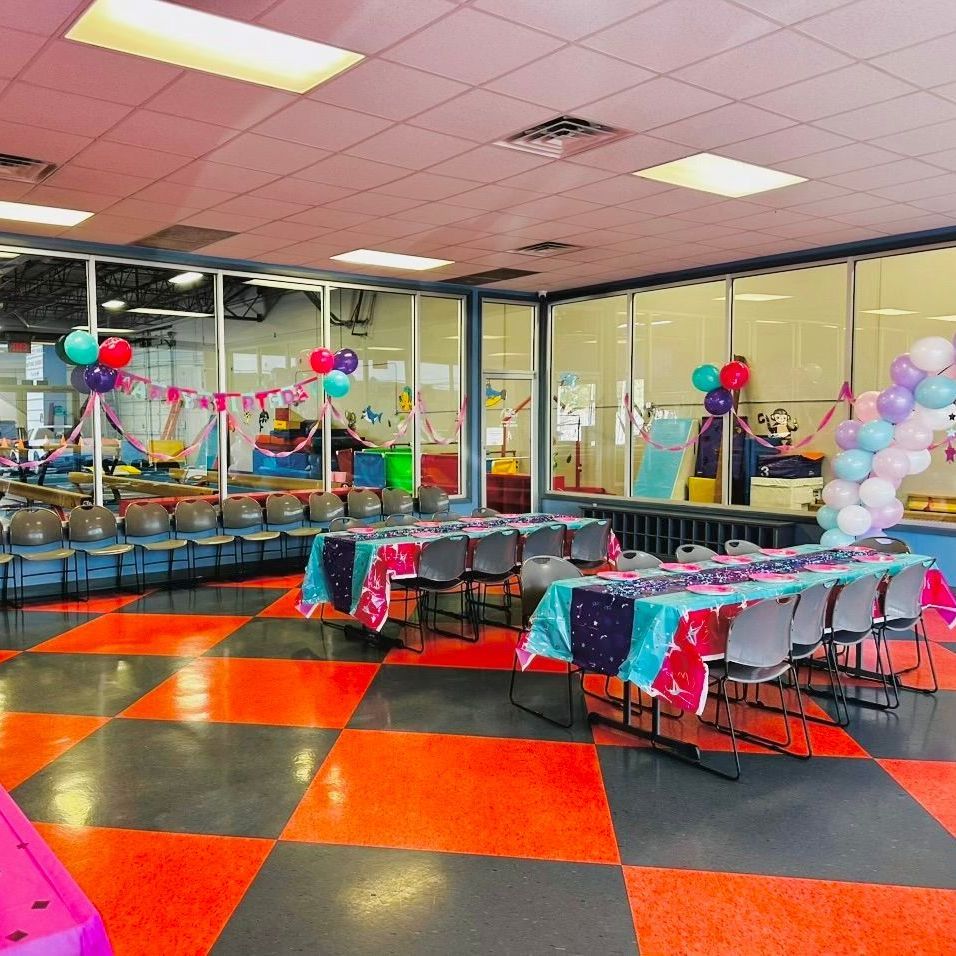 A room with tables and chairs and balloons on the ceiling