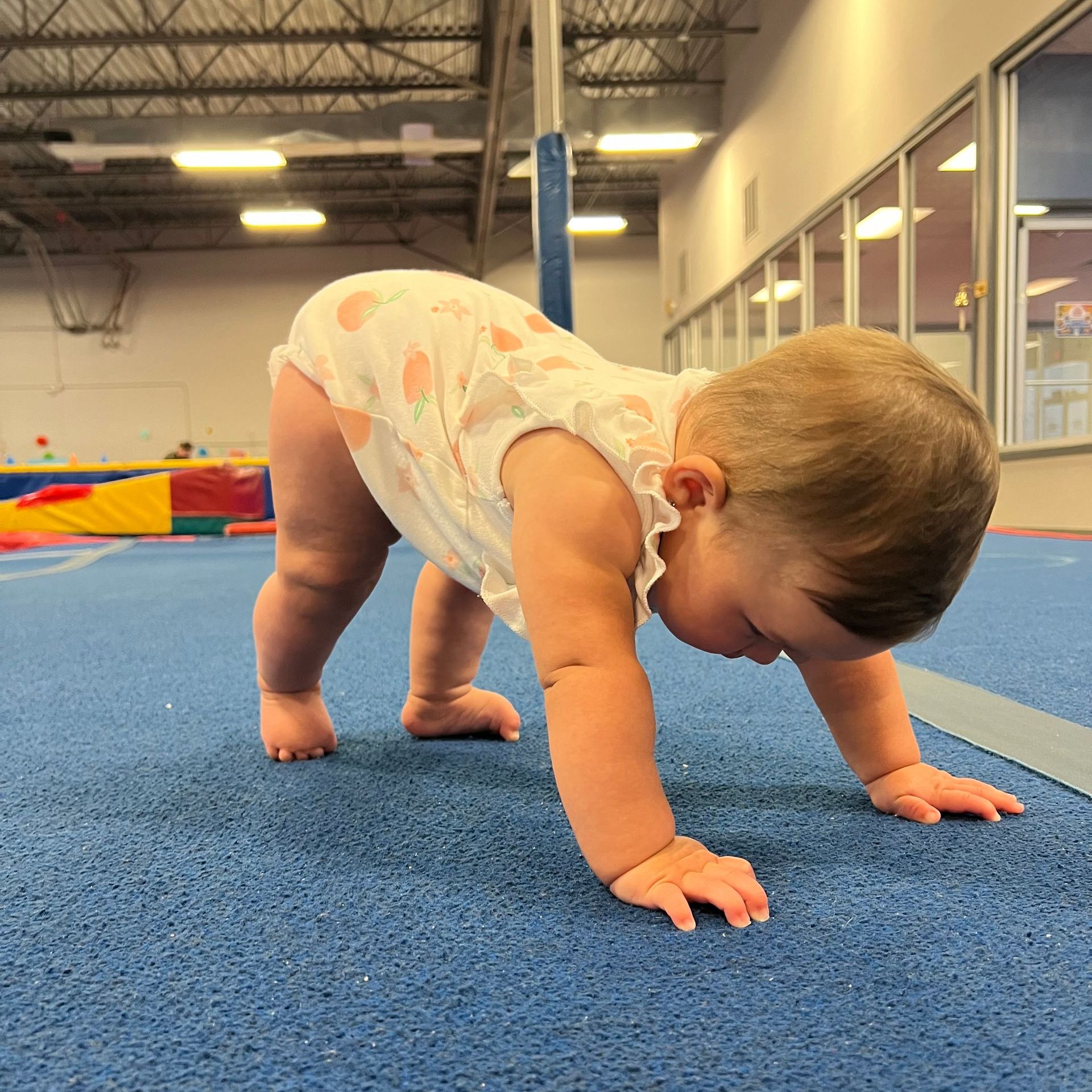 A baby is crawling on the floor in a gym