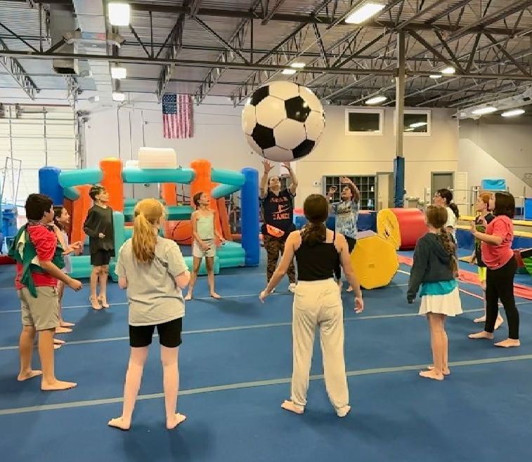 A group of children are playing with a soccer ball in a gym