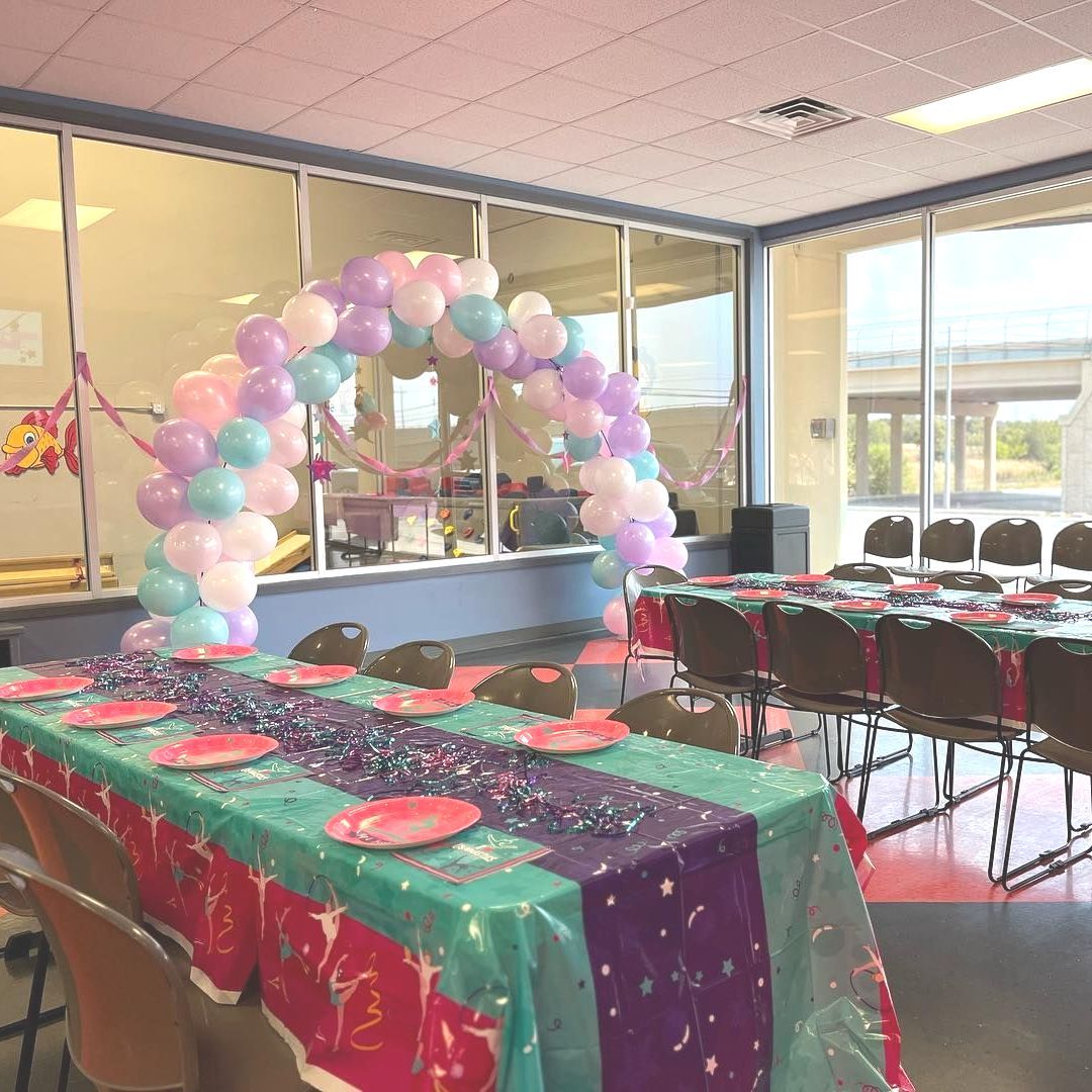 A room with tables and chairs and balloons on the wall