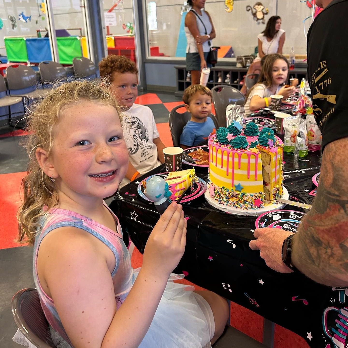 A little girl is sitting at a table with a cake on it.