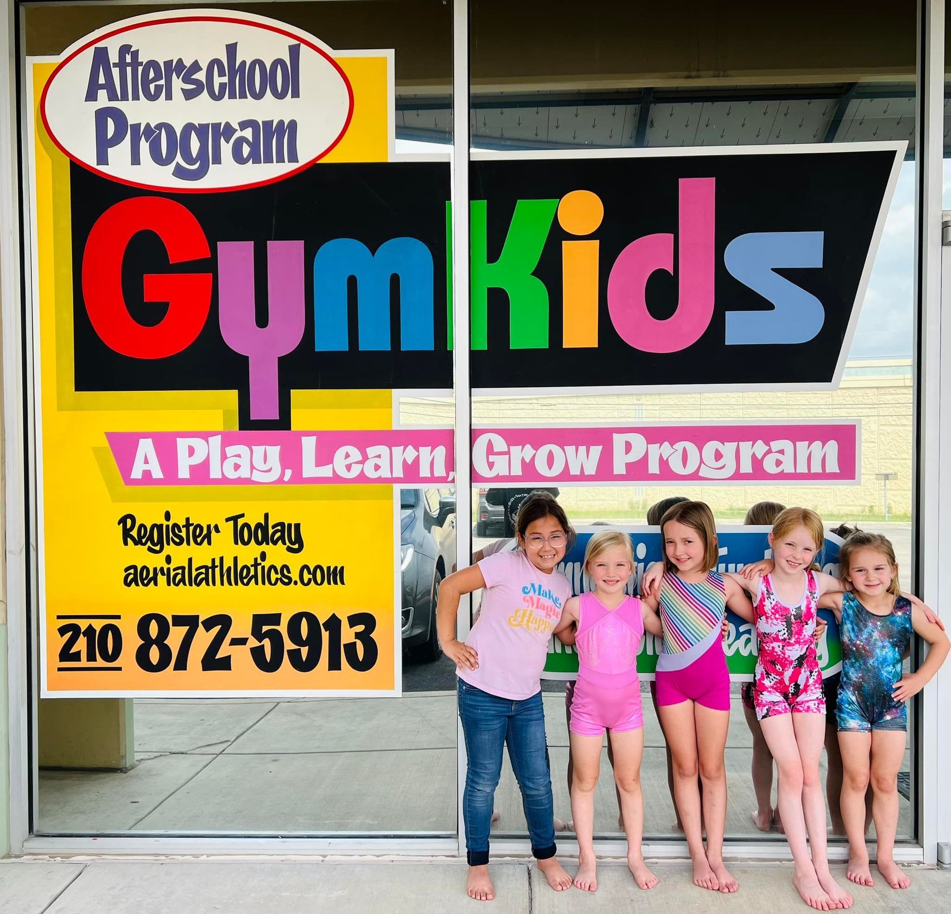 A group of young girls standing in front of a gym kids sign