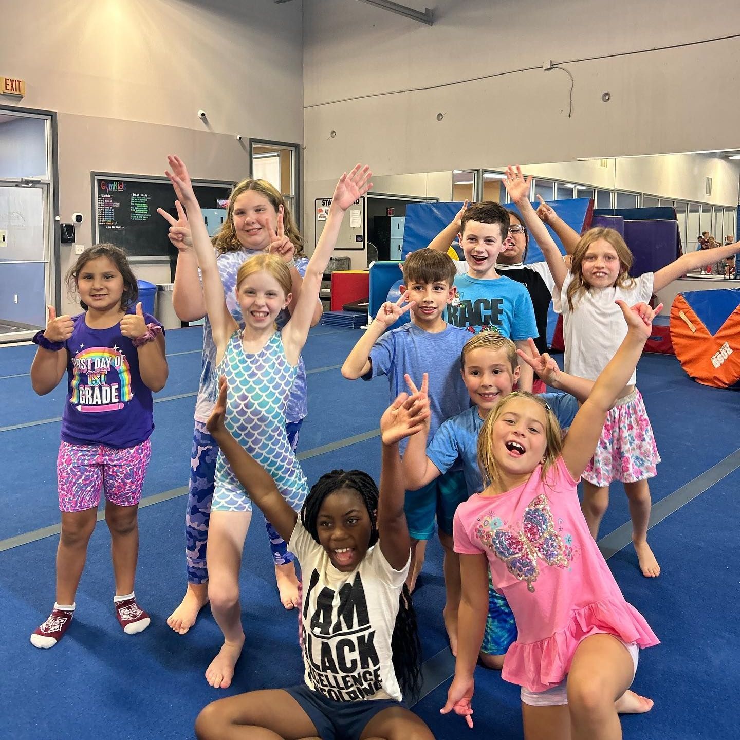 A group of children are posing for a picture and one girl is wearing a black shirt