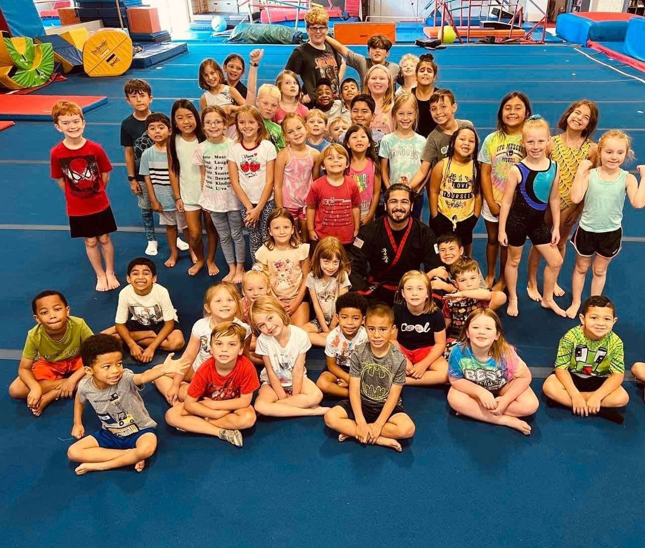 A group of children are posing for a picture in a gym.