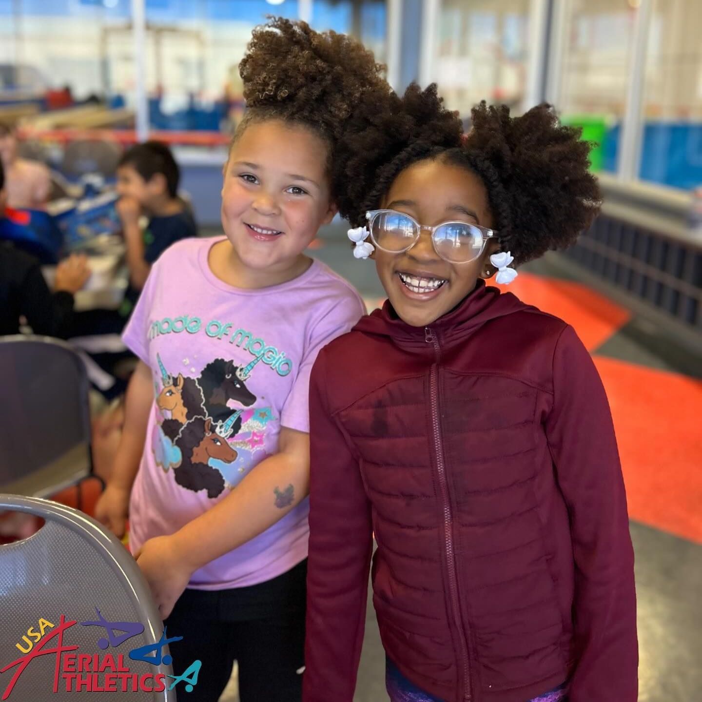 Two young girls are posing for a picture in front of a sign that says usa kids theatres