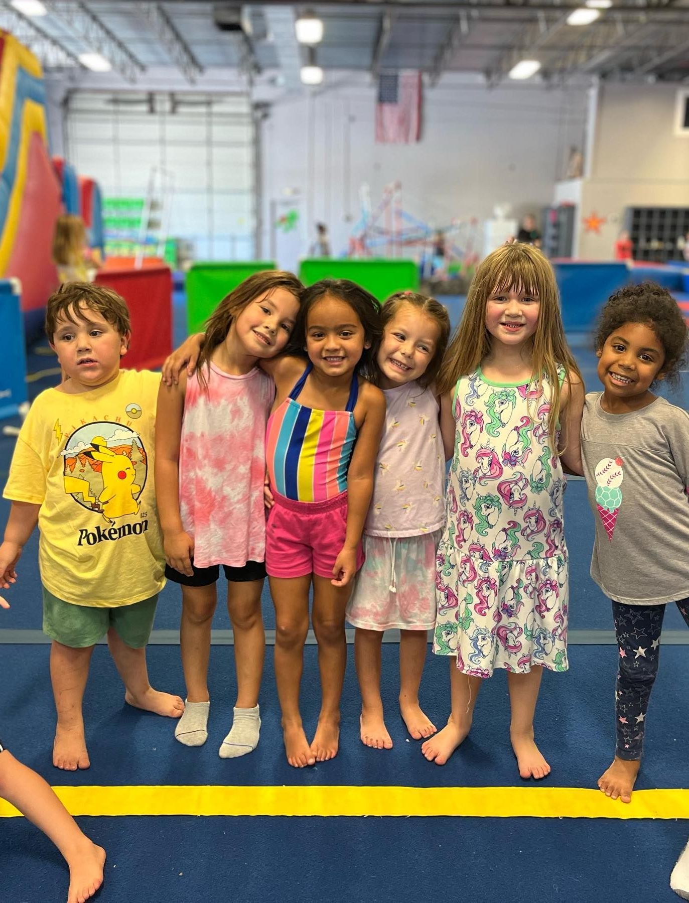 A group of young children are posing for a picture in a gym.