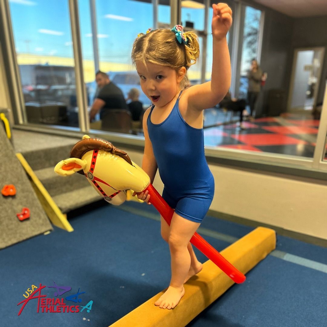 A little girl balances on a wooden balance beam