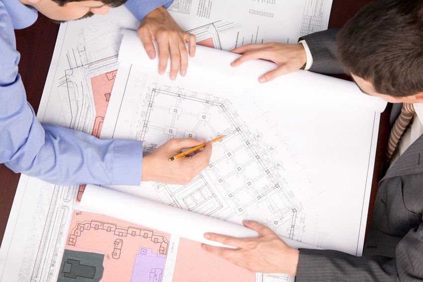 Above view of engineers over blueprints during work planning