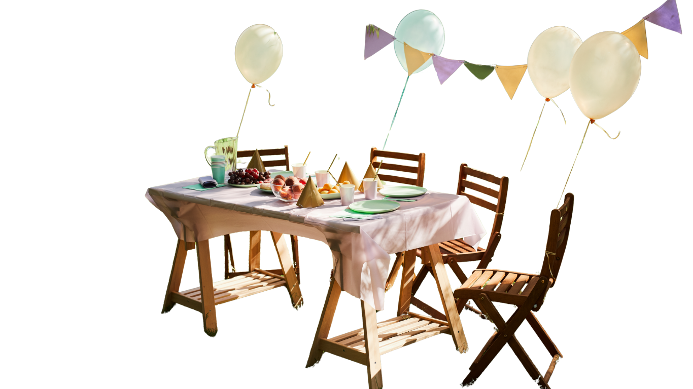 Outdoor party table set with balloons and decorations; three wooden chairs surround the table set for a meal.