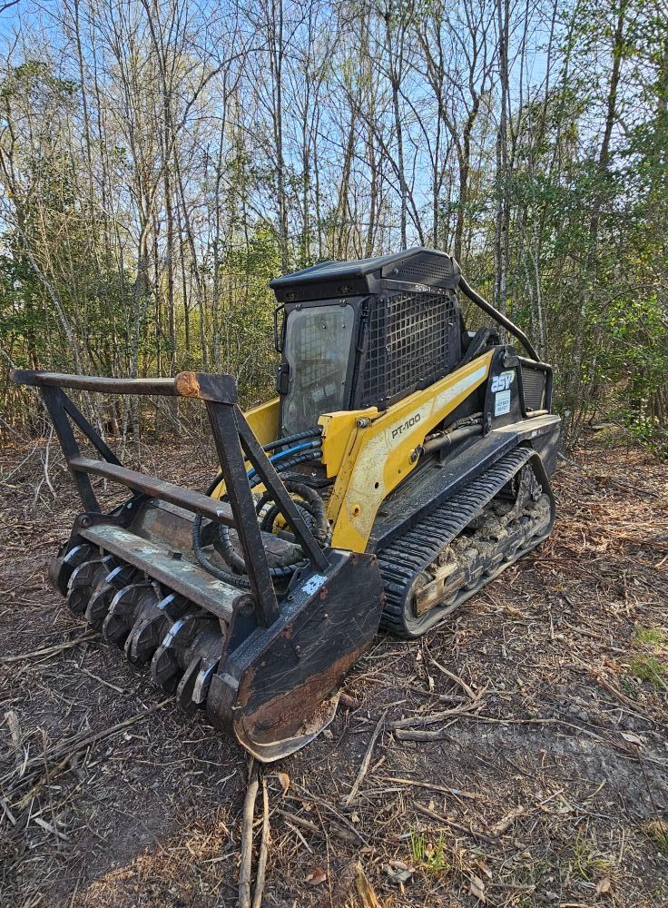 A yellow and black bulldozer is parked in the middle of a forest.