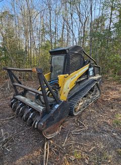 A yellow and black bulldozer is parked in the middle of a forest.
