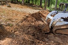 A bulldozer is digging a hole in the dirt in the woods.
