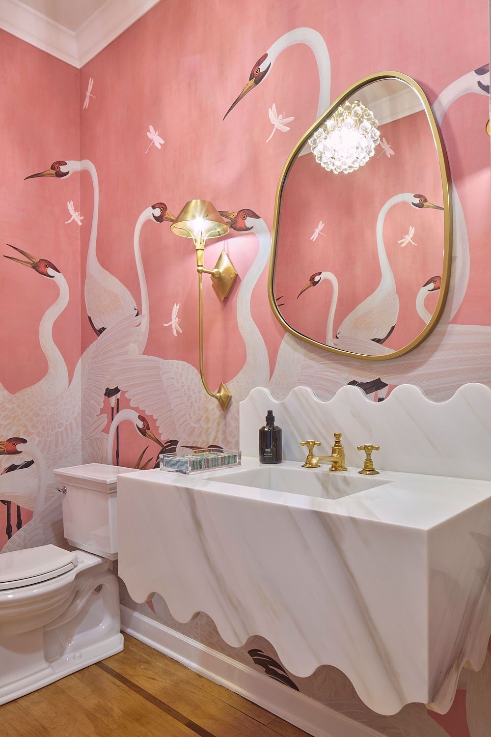 Pink swan wallpaper bathroom with marble sink and gold accents.