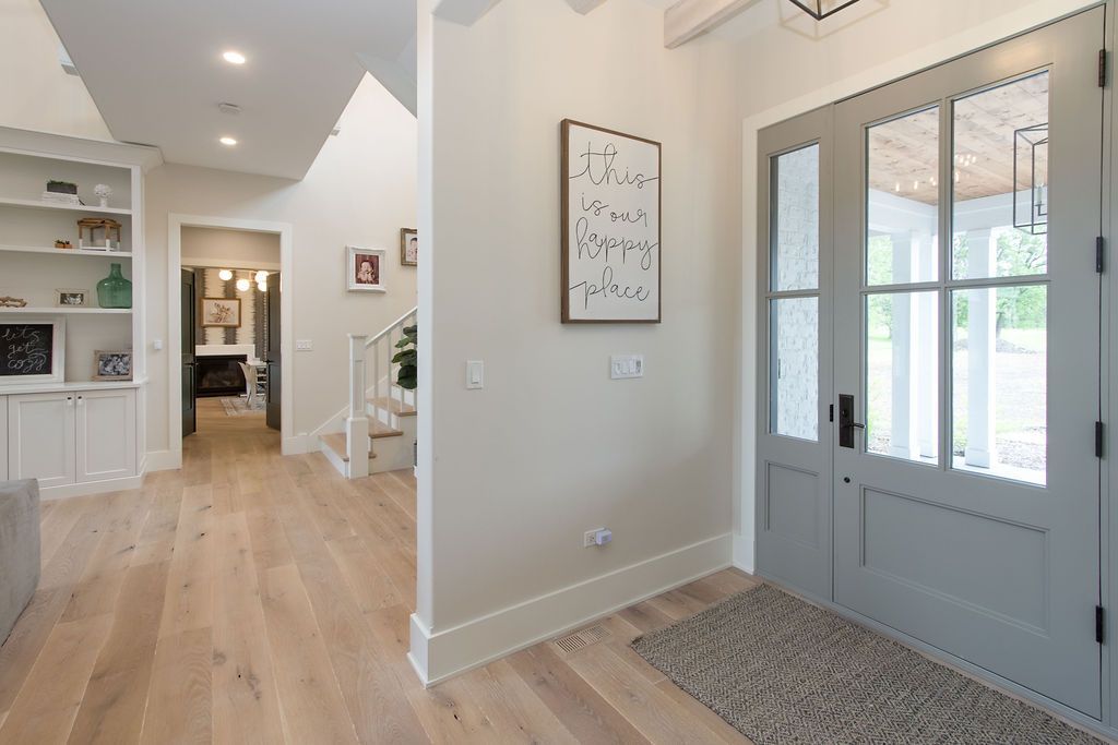 Entryway with gray double doors, wooden floor, and a framed sign.
