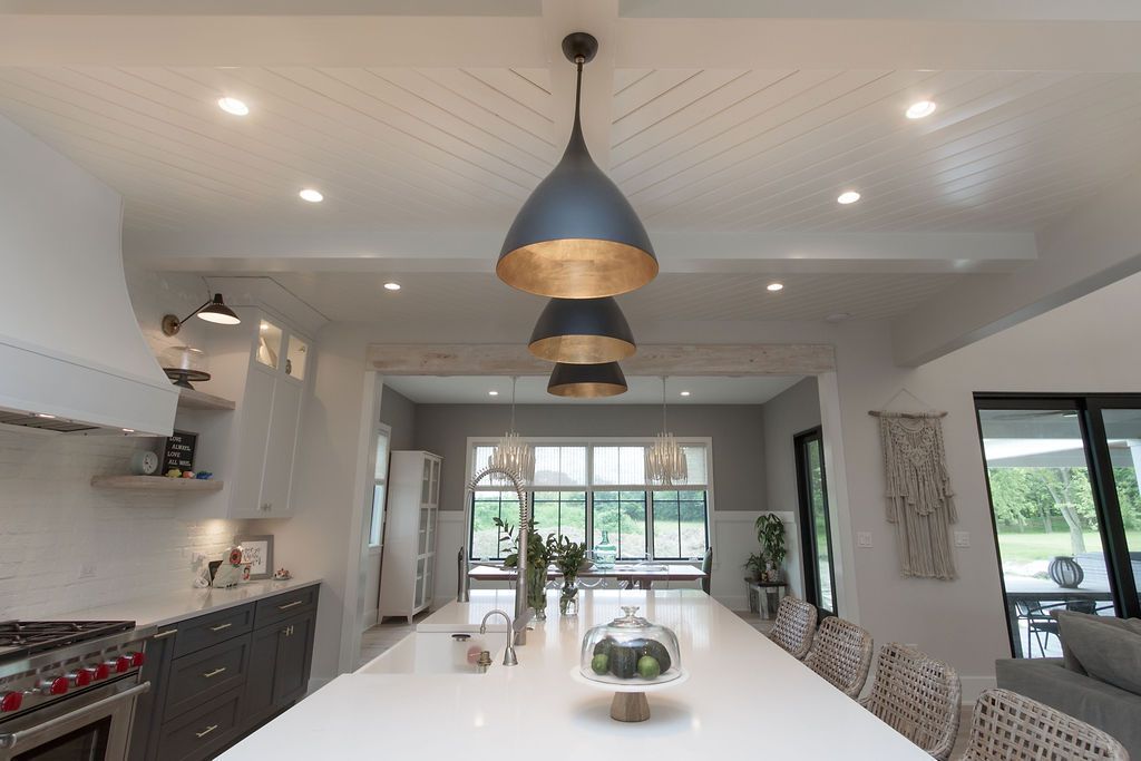 Modern kitchen with large island, pendant lights, and large windows looking outside.