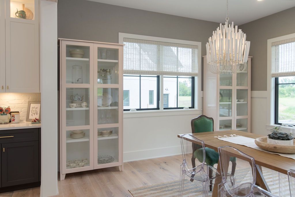 Dining room with light-colored wood floor, two glass-front cabinets, a dining table, and a modern chandelier.