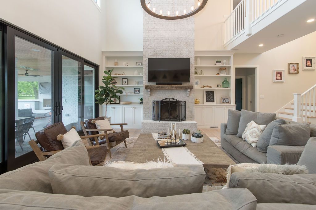Living room with gray sofa, brick fireplace, built-in shelves, and large windows.