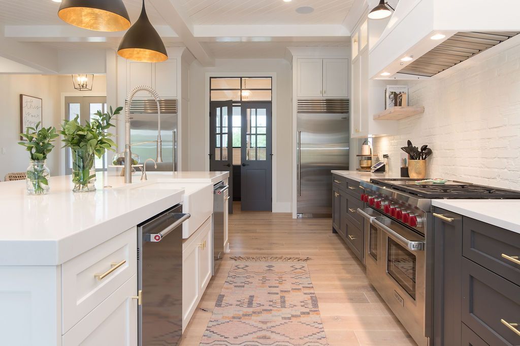 Modern kitchen with white island, stainless steel appliances, dark gray cabinets, and a rug.