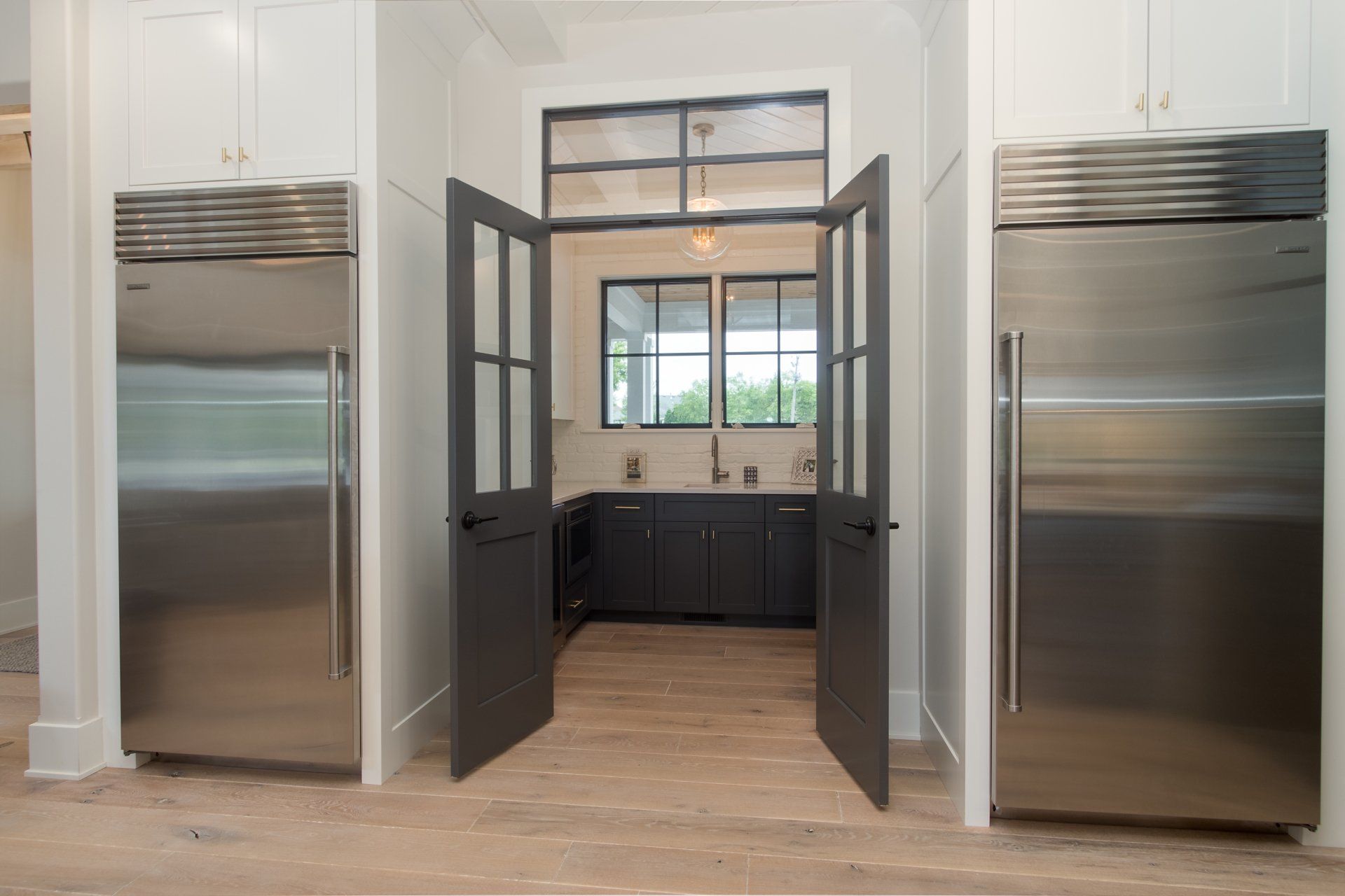 A kitchen with two stainless steel refrigerators and two stainless steel freezers
