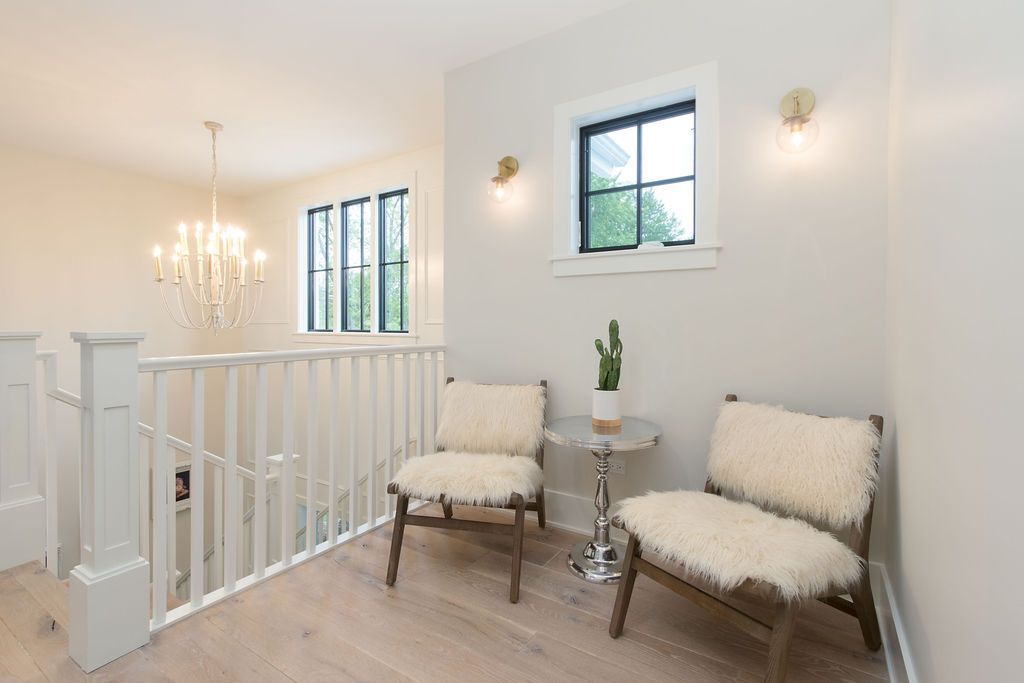 A light-filled hallway with two chairs, a small table, and a cactus plant.